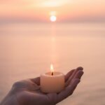 que es duImagen de una mano sosteniendo una vela frente al mar al amanecer para el blog de Gaby Oviedo
